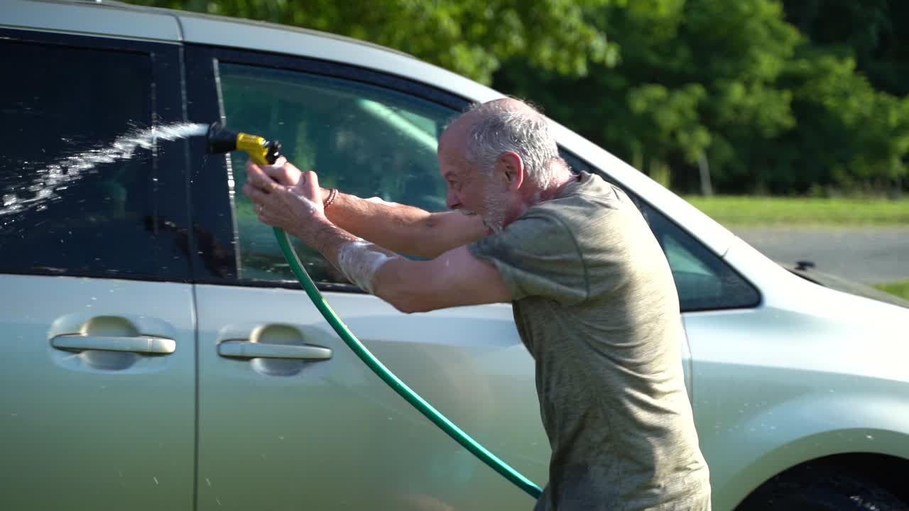 loco con manguera lavando auto y agitando agua en el aire en cámara lenta