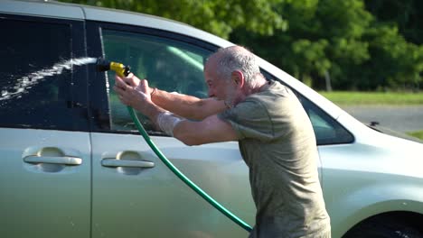 crazy man with hose washing car and flailing water in the air in slow motion