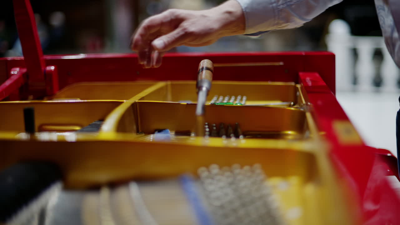 Close up of a man fixing a red piano
