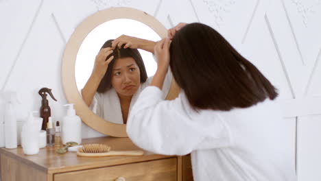 woman checking for gray hair in a mirror