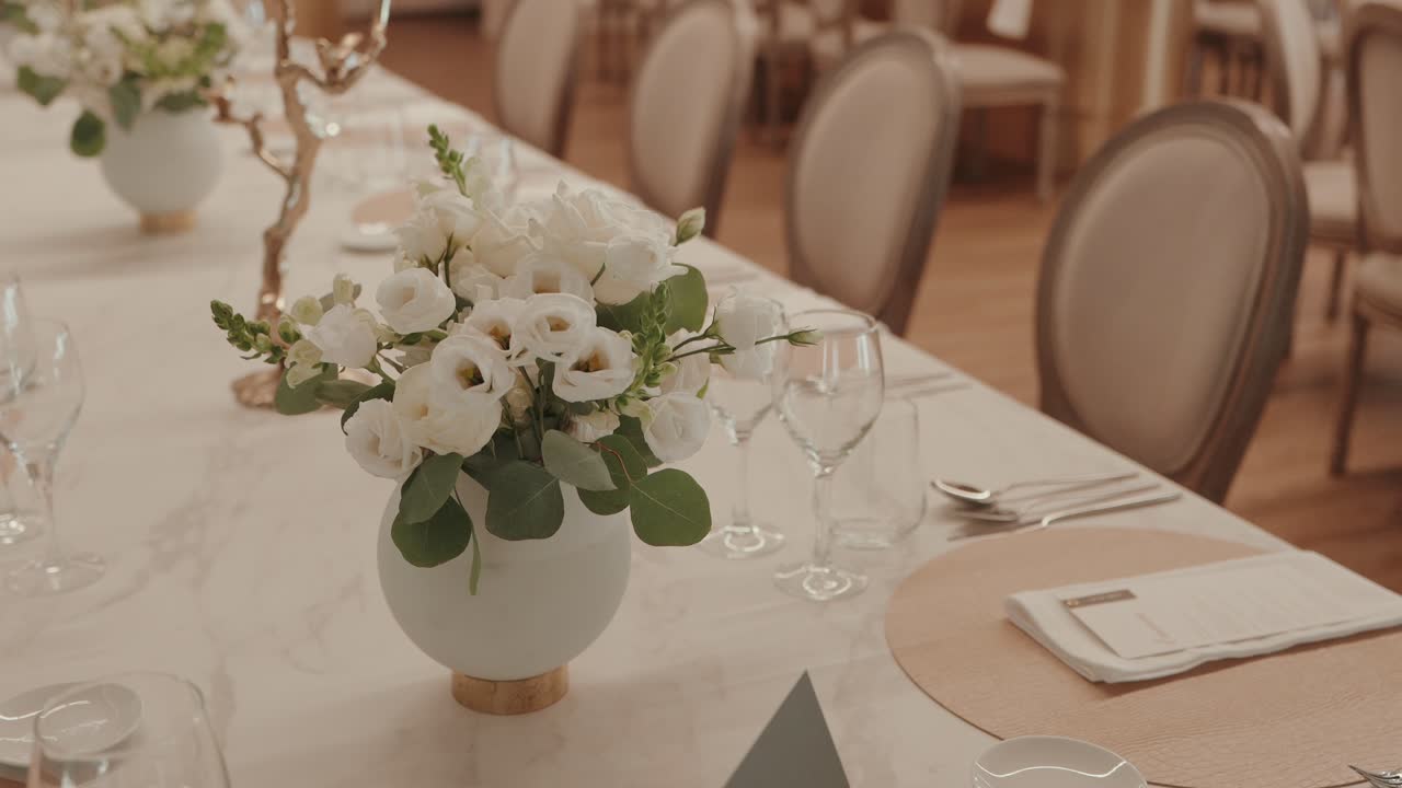 close up of wedding table with white flower centerpiece vase glasses and cutlery setup