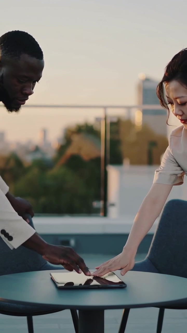 Vertical video: Meeting man in blazer and woman in blouse placing tablet on rooftop reviewing file