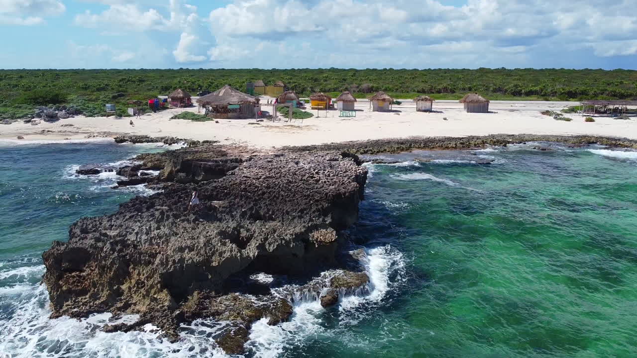 cabañas de playa en la playa rocosa de la isla de cozumel con olas turquesas rompiendo en méxico en un día soleado, antena