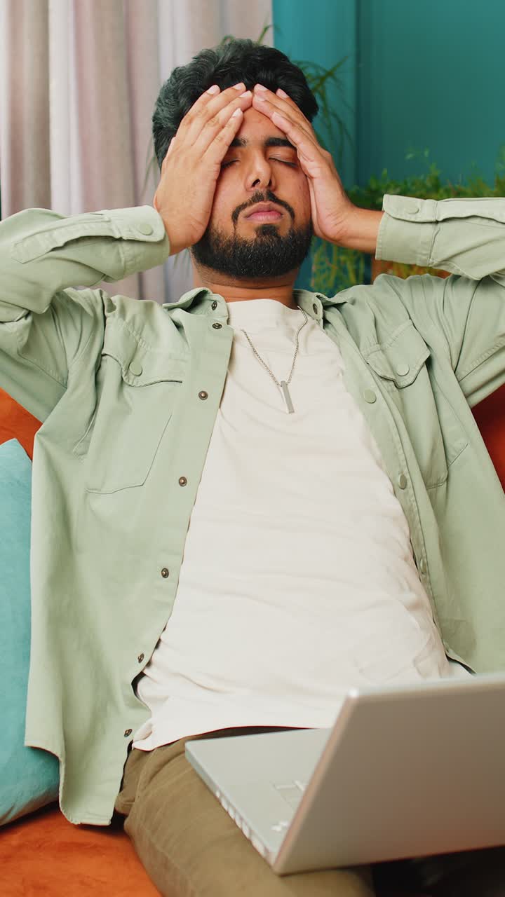 Tired indian man freelancer use laptop suffering from headache problem tension and migraine stress