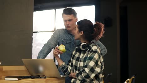 Two-young-people,-young-man-and-a-girl,-typing-something,-using-laptop.-Spending-time-together.-Open-co-working-space-indoors-area