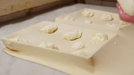 handmade focaccia di recco preparation, soft dough and cheese on kitchen counter