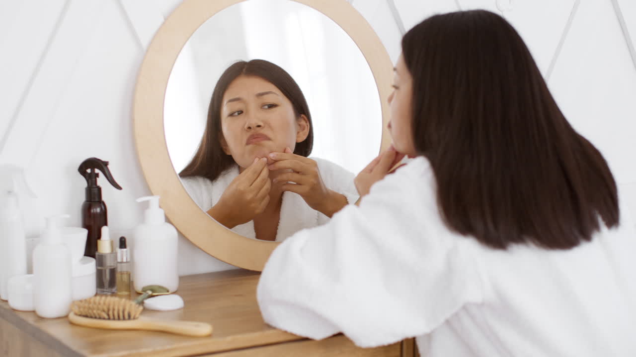 Woman looking at pimple in mirror