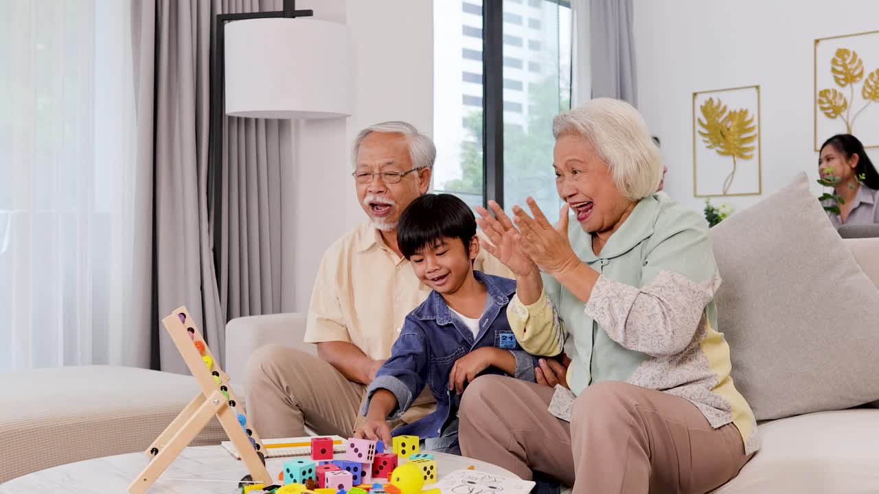 明るくモダンなリビングルームで、年配の夫婦と幼い男の子が数学のおもちゃで楽しそうに遊んでいます。