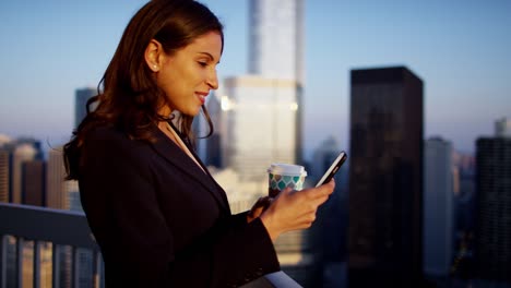 una mujer de negocios hispana usando un teléfono inteligente en el techo al amanecer