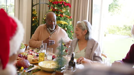 Feliz-Y-Diversa-Pareja-De-Ancianos-Hablando-En-La-Mesa-De-La-Cena-De-Navidad-Con-Amigos,-Cámara-Lenta