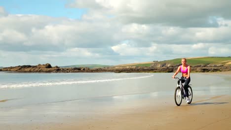 athletic blonde biking on the beach