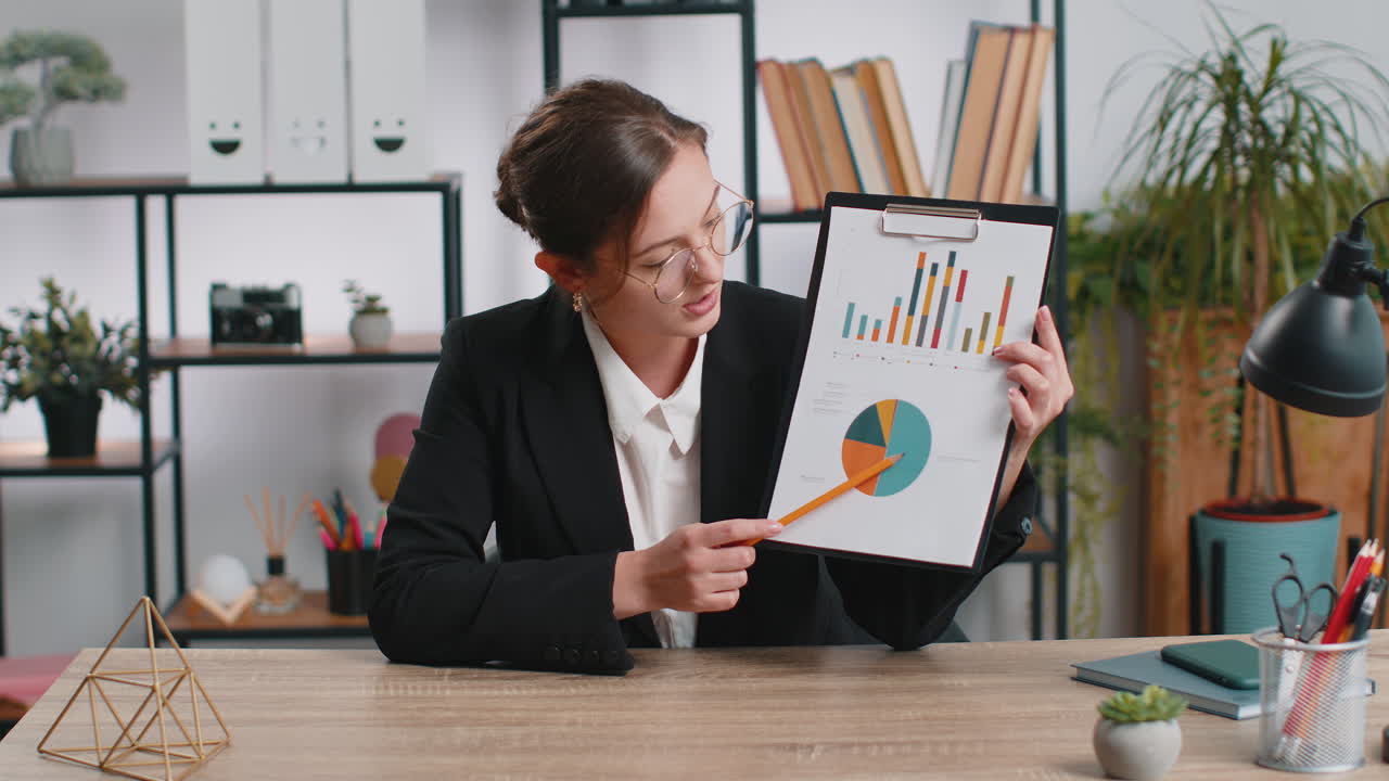 Perspectiva de mujer de negocios trabajando en la oficina, hablando en una videollamada y mostrando análisis gráficos.