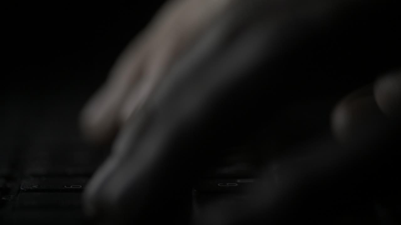 manos escribiendo en un teclado de portátil por la noche