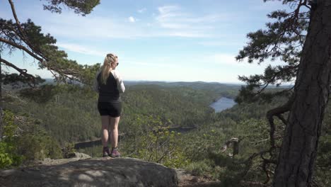 great scenery of norwegian forest mountains with woman hiker standing on viewpoint