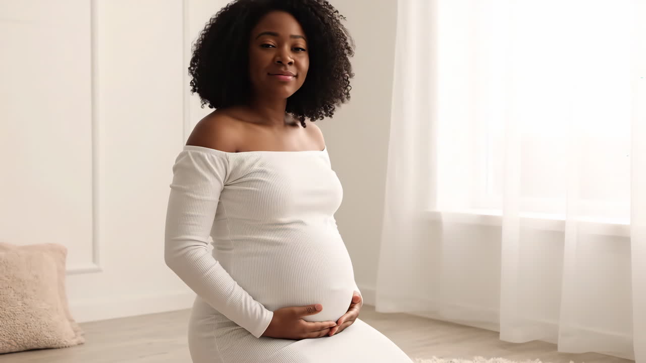 Une belle femme noire enceinte posant en robe blanche