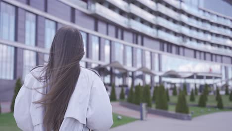 a happy woman is walking in front of an office building. she carries her things in a box. she has quitted her job.