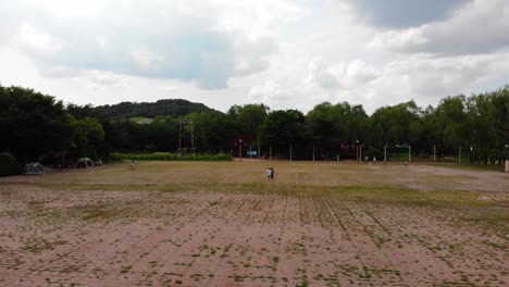 aerial shot behind children walking and playing at park