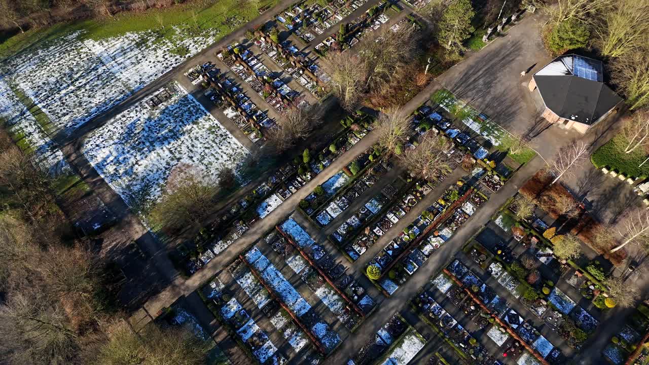 Snowy winter day on american cemetery with snow-covered tombs at sunrise. Aerial top down flyover shot. Rural area of american countryside.