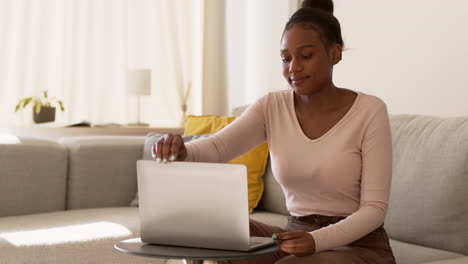 mujer joven trabajando en una computadora portátil en casa