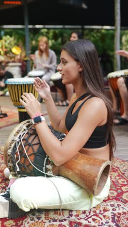 woman playing djembe drum in a group setting