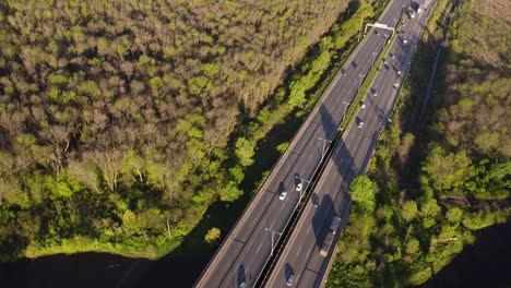 aerial view of dynamic movement of vehicles on interstate expressway amidst beautiful greenery during sunset