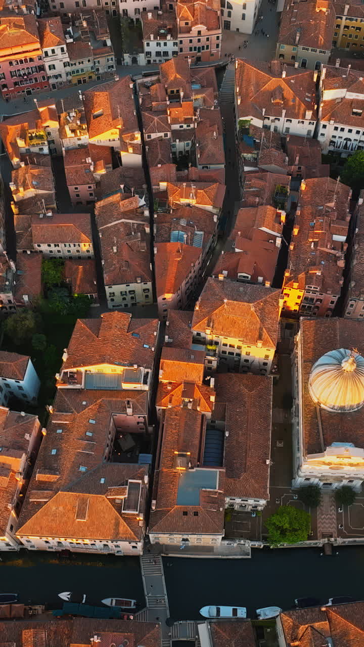 Straight down aerial drone shot of houses surrounding The Basilica di Santa Maria Gloriosa dei Frari rooftop in Venice, Italy. Vertical