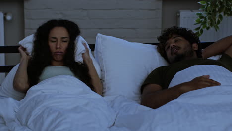 couple in bed, one sleeping, one upset