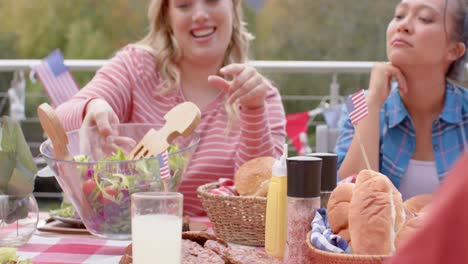 happy diverse group of friends eating and talking at dinner table in garden, slow motion