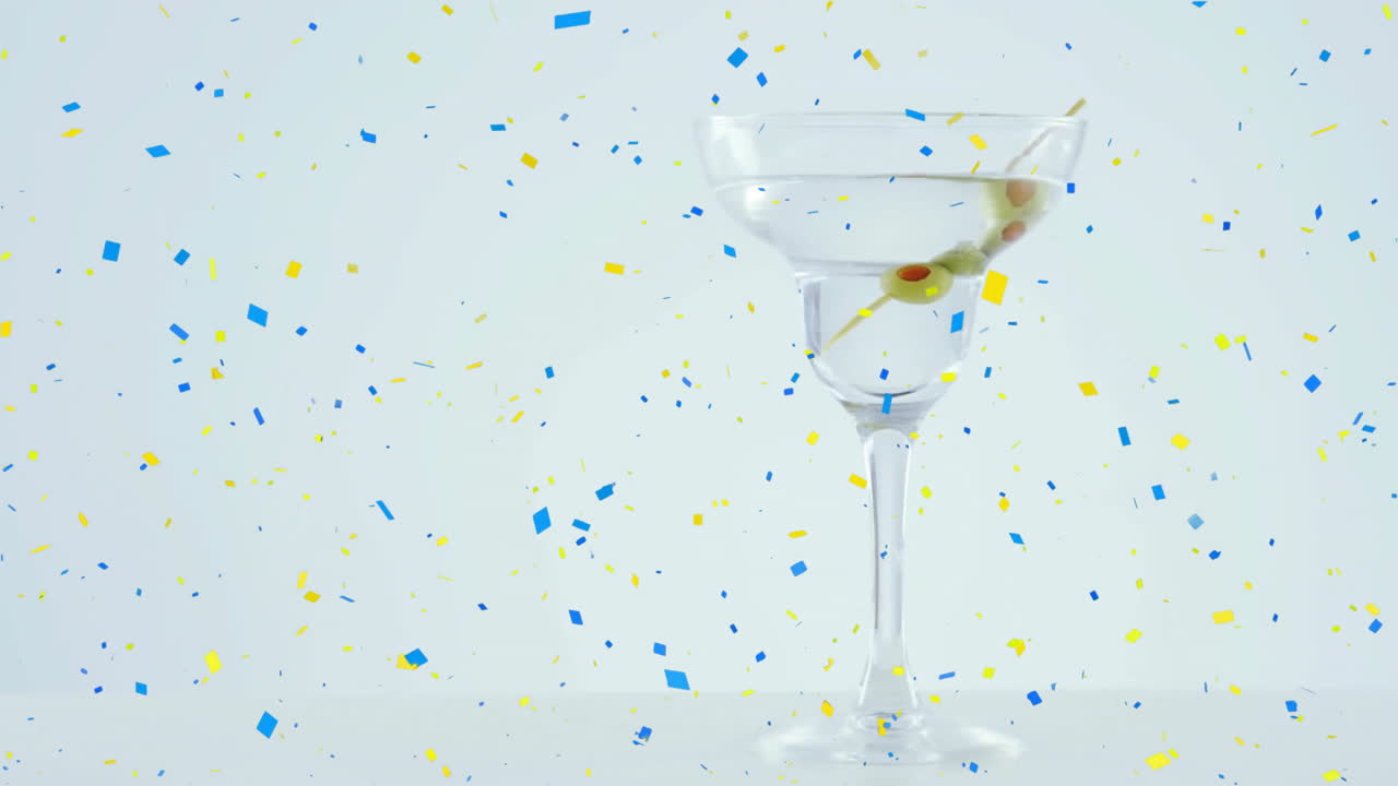 animación de confeti sobre un vaso de martini con oliva en un fondo blanco