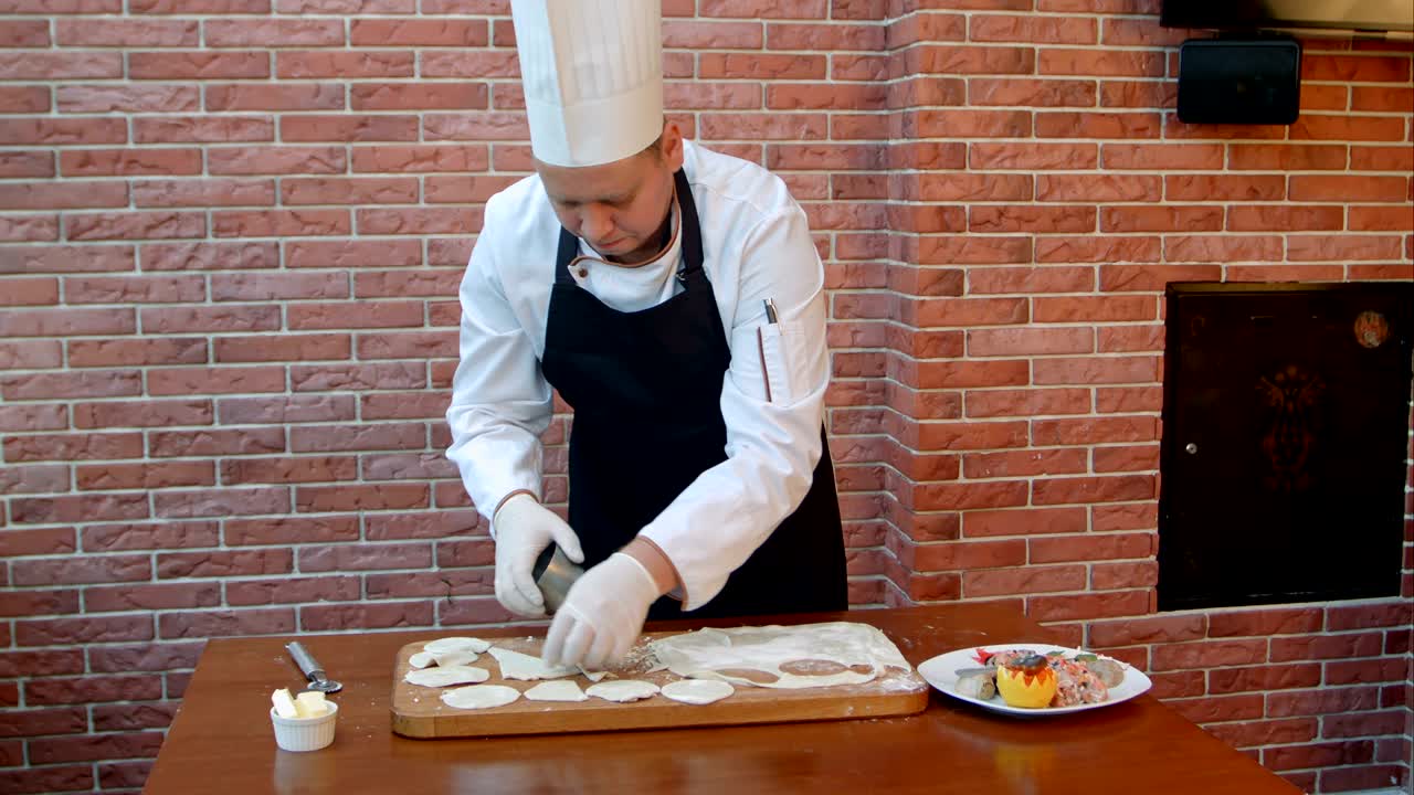 cocinero cortar círculos de la masa de galletas crudas costura enrollada en una tabla de madera