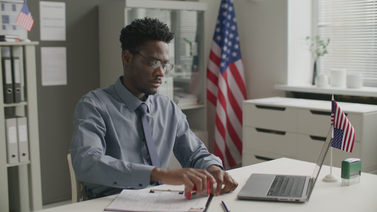 Visa Officer Stamping Rejection on Documents at Desk in American Consulate