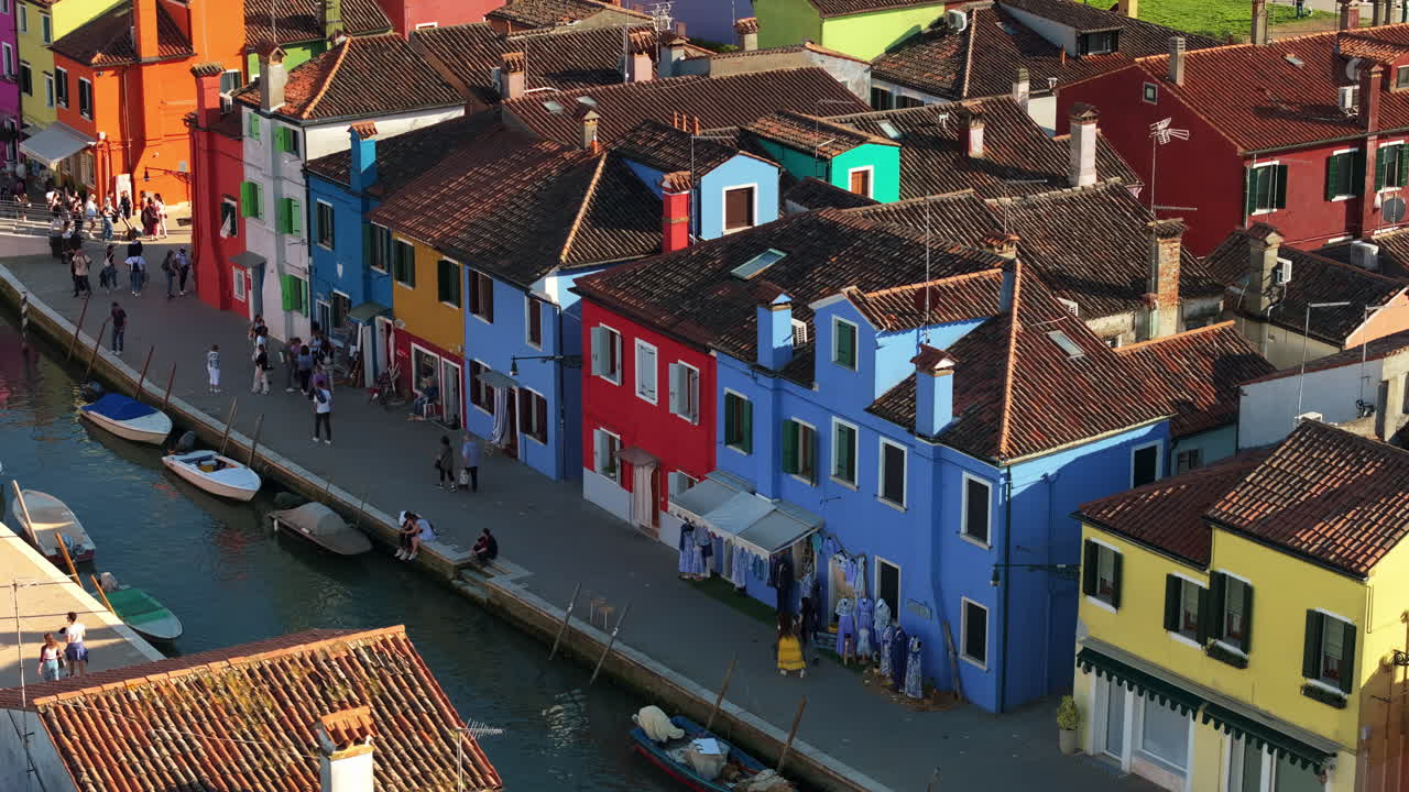 Aerial drone view of boats on the sides of a canal near the colourful houses of Burano island, Italy