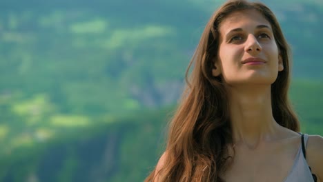 a woman standing in a field with mountains in the distance looking happy and smiling with laughter