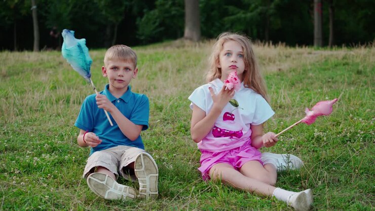 Bambino al parco con lo zucchero filato. Adorabili bambini che mangiano zucchero filato all'aperto.