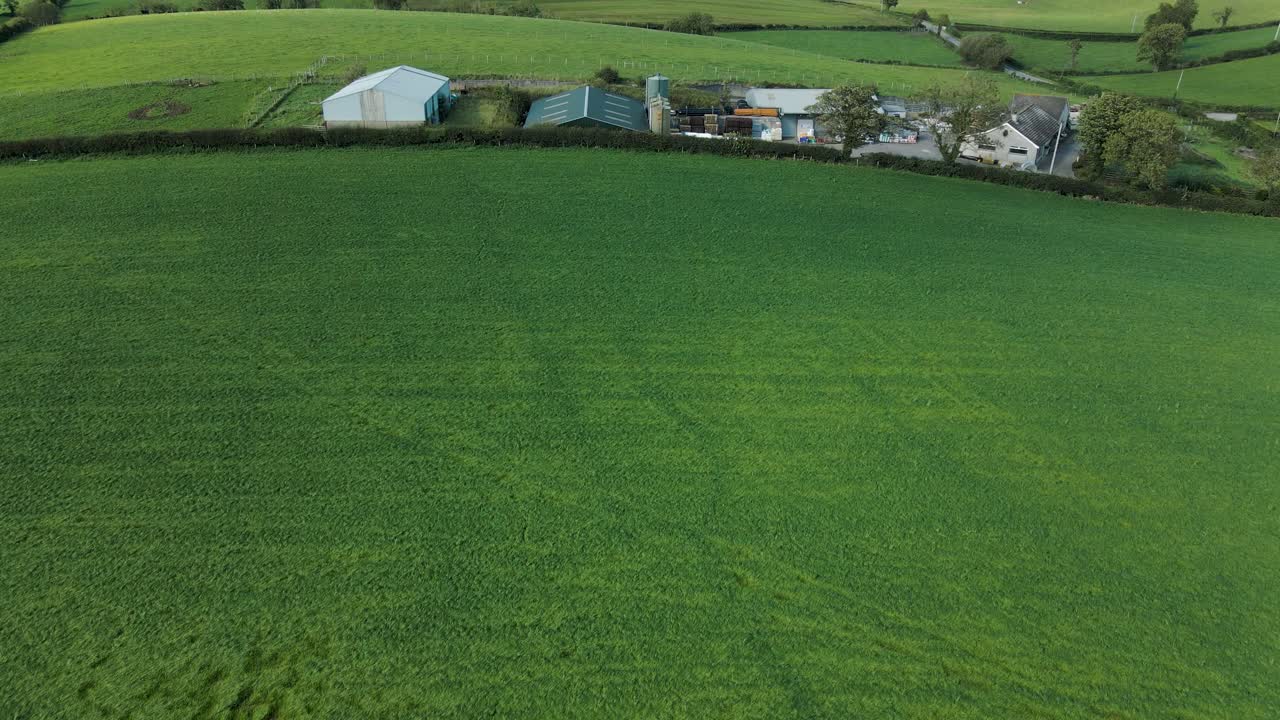 Vippende luftfoto af lader og bondehuse på det irske landskab