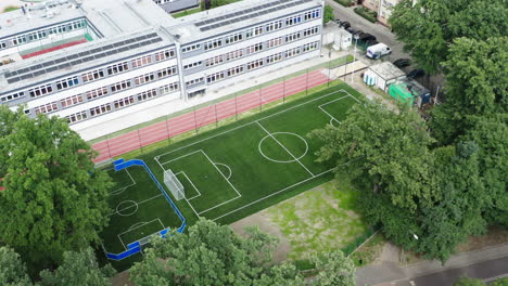 right orbiting aerial shot of a brand new soccer field and running track next to the elementary school in poland, 4k drone