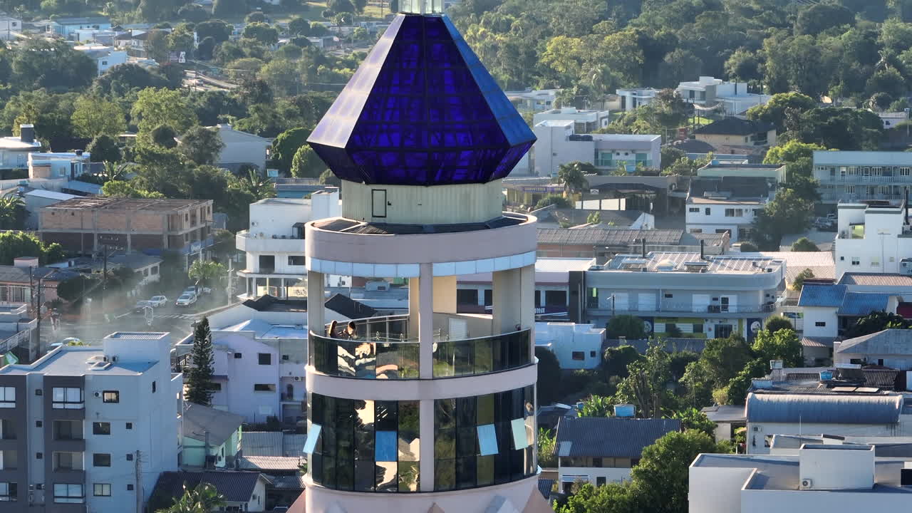 Torre miradouro de igreja se eleva a uma cruz acima de uma cúpula de cristal azul e colinas distantes em uma revelação dramática em teleobjetiva ascendente