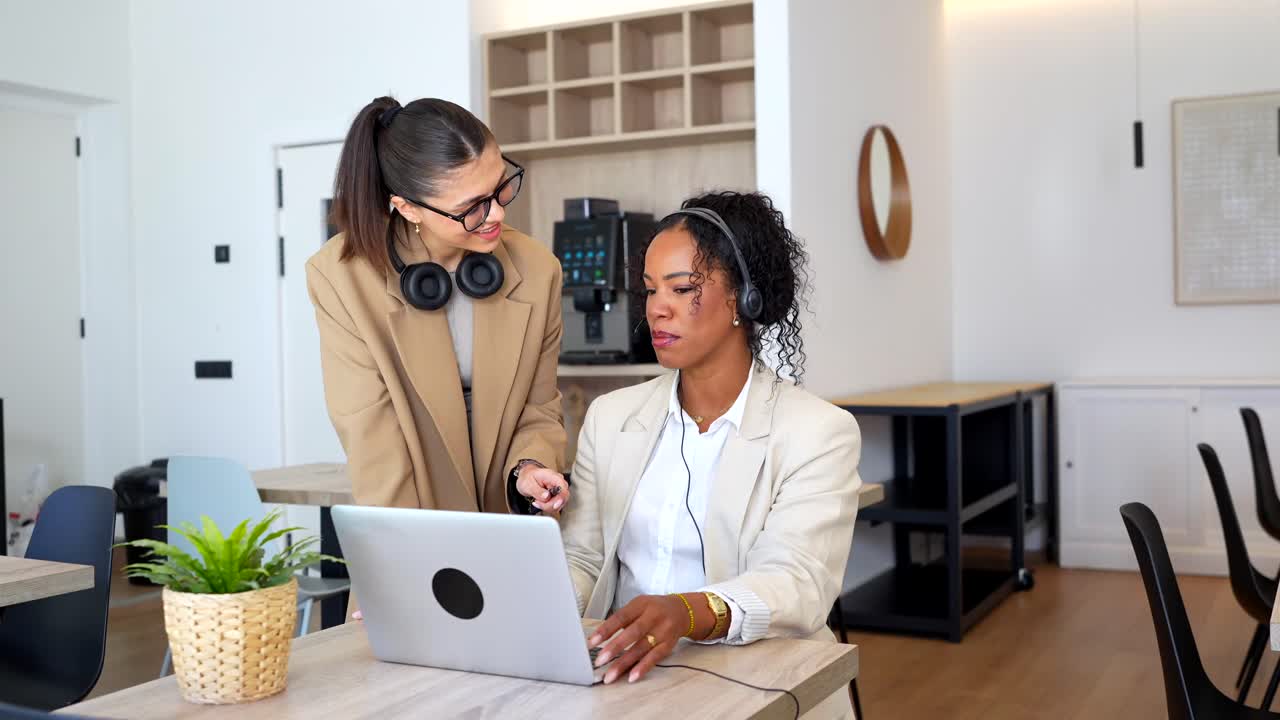 Two Businesswomen Collaborating on a Laptop in an Office Setting