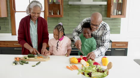 Happy-african-american-grandparents-and-grandchildren-chopping-vegetables-in-kitchen,-slow-motion