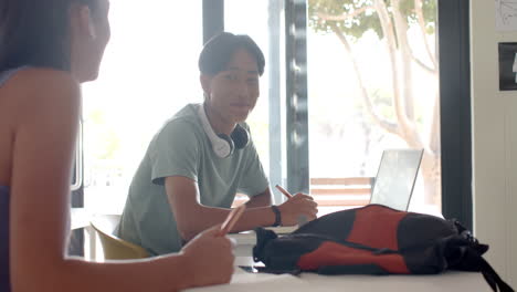 teenager with headphones studying with laptop and notebook in high school classroom