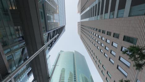 looking up at a cluster of tall, contemporary office buildings in a bustling urban financial district