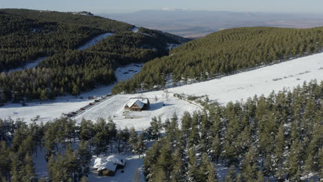 Deserted-ski-hut-and-slope-amid-dramatic-green-and-white-of-snow-and-pine-trees