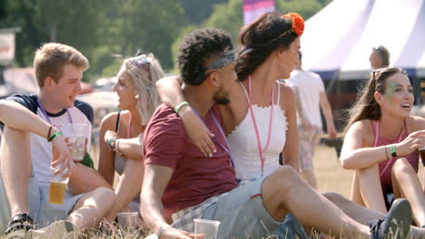 friends sitting on grass taking selfie at a music festival