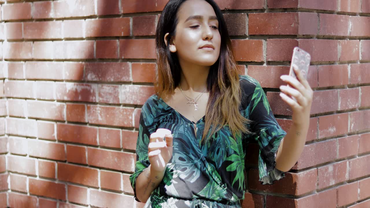 모바일을 사용하여 벽돌 벽에 기대어 여자