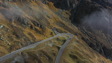 descending drone footage of the susten pass in the swiss alps in switzerland with a vehicle driving on the road