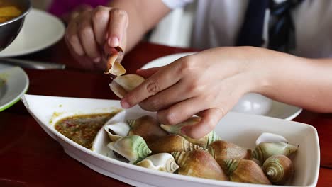 hands peeling seafood shells at a dining table