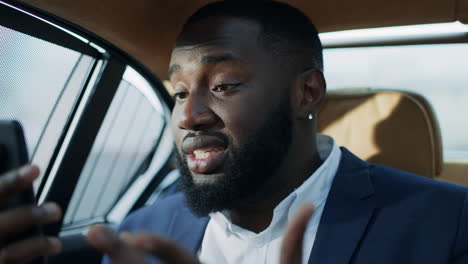 stressed african man having video call at car. angry afro guy getting bad news