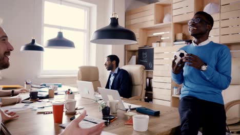 african american worker talking to company boss. happy mixed ethnicity colleagues work in trendy loft office space 4k