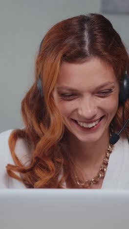 young positive caucasian woman support operator uses headset and laptop