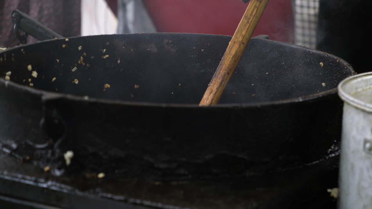 Cooking And Stirring Kettlecorn In Cauldron Using Wooden Spoon